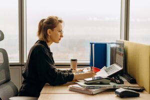 woman facing the computer with books on the table
